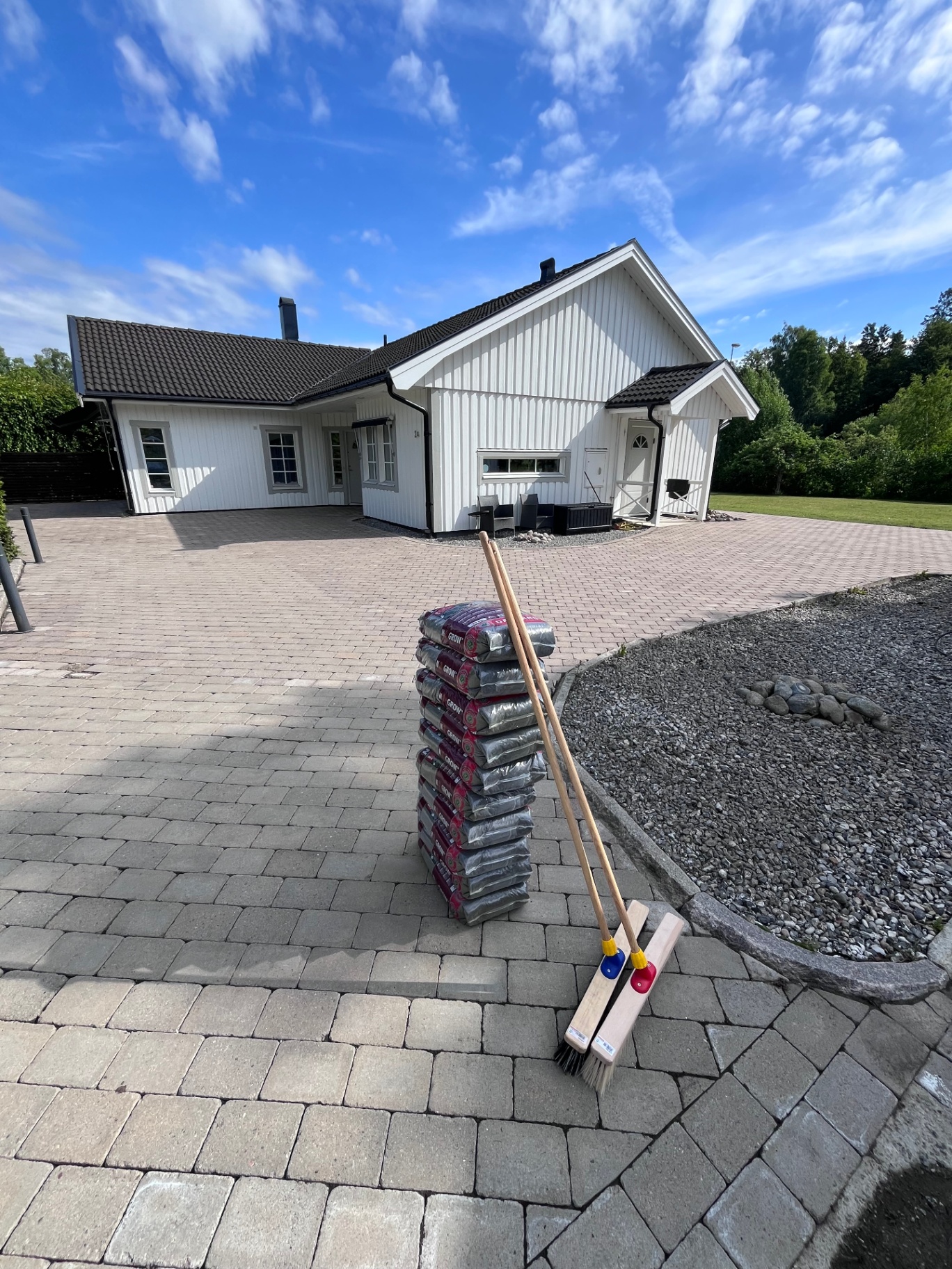 Fogsand och sopborstar framför villauppfart inför fogsandning